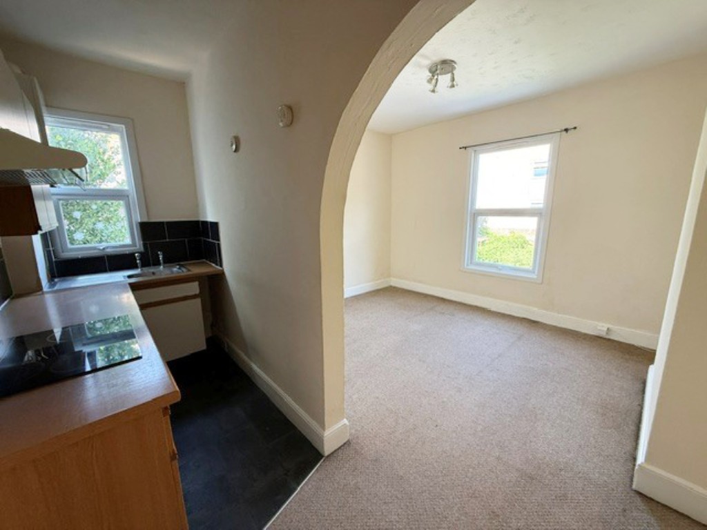 Lot: 180 - VACANT FIRST FLOOR FLAT FOR IMPROVEMENT - Living Room with archway to fitted kitchen area